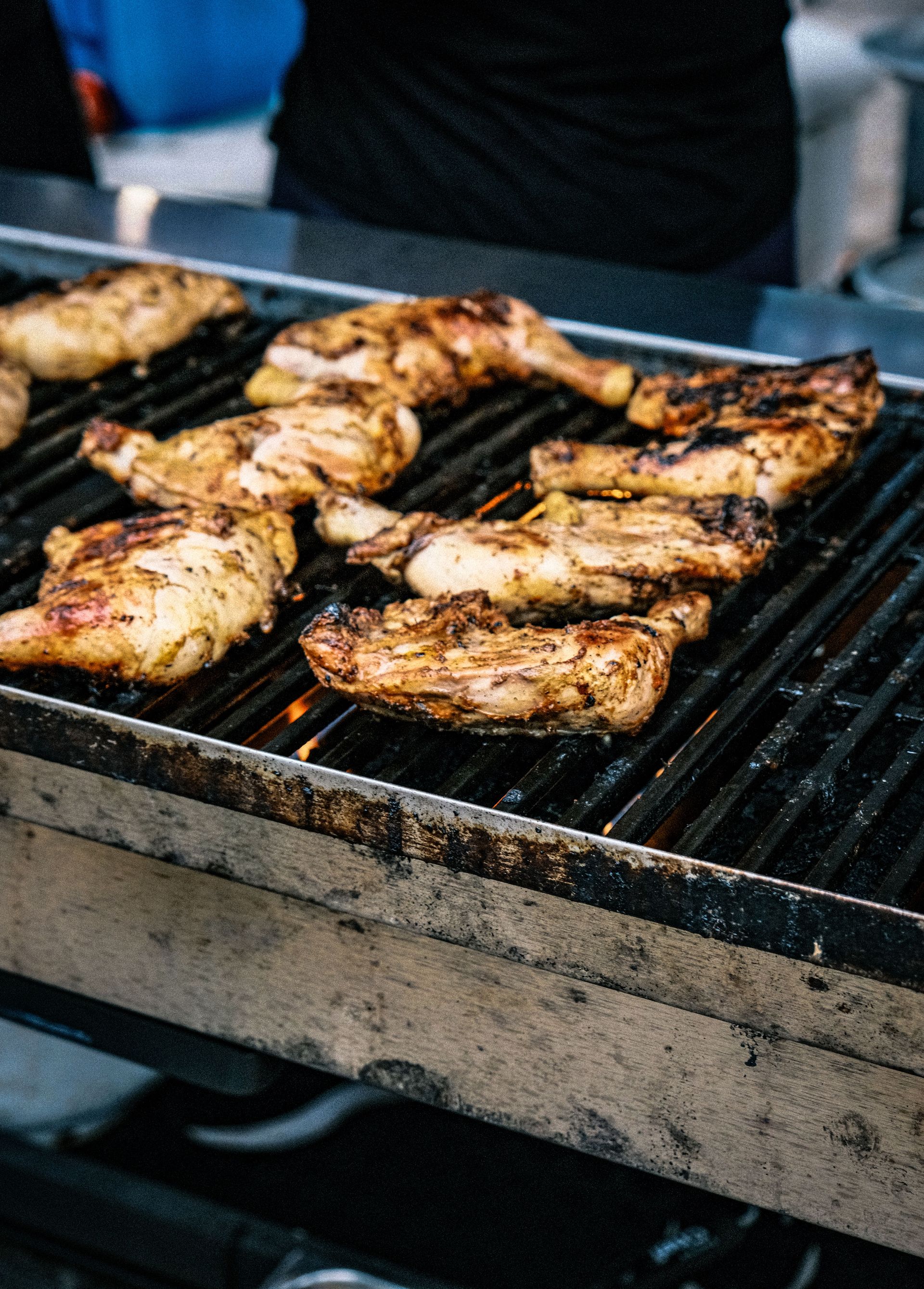 Juicy grilled chicken pieces sizzling on an outdoor barbecue grill.