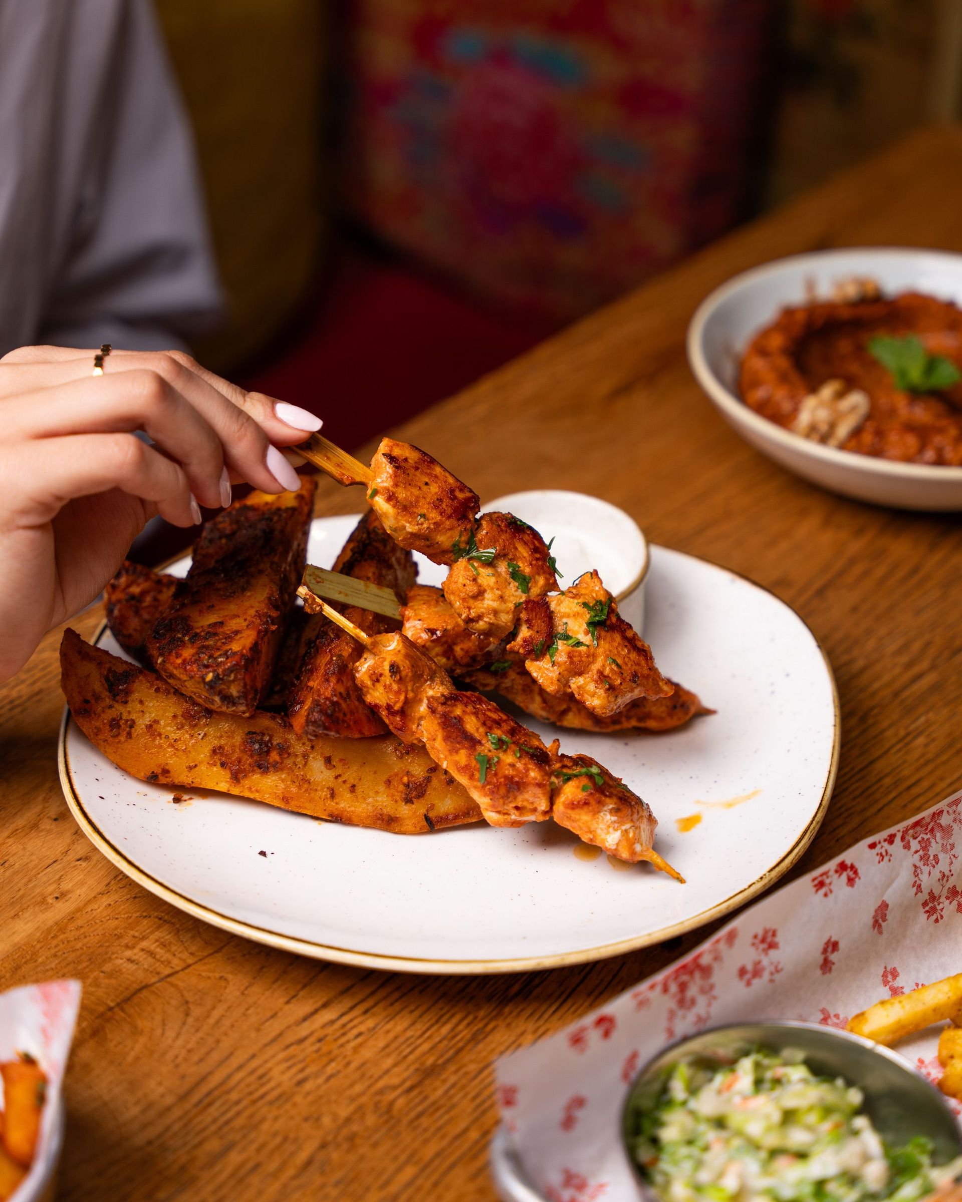 Close-up of gourmet chicken skewers and potato wedges served on a plate.