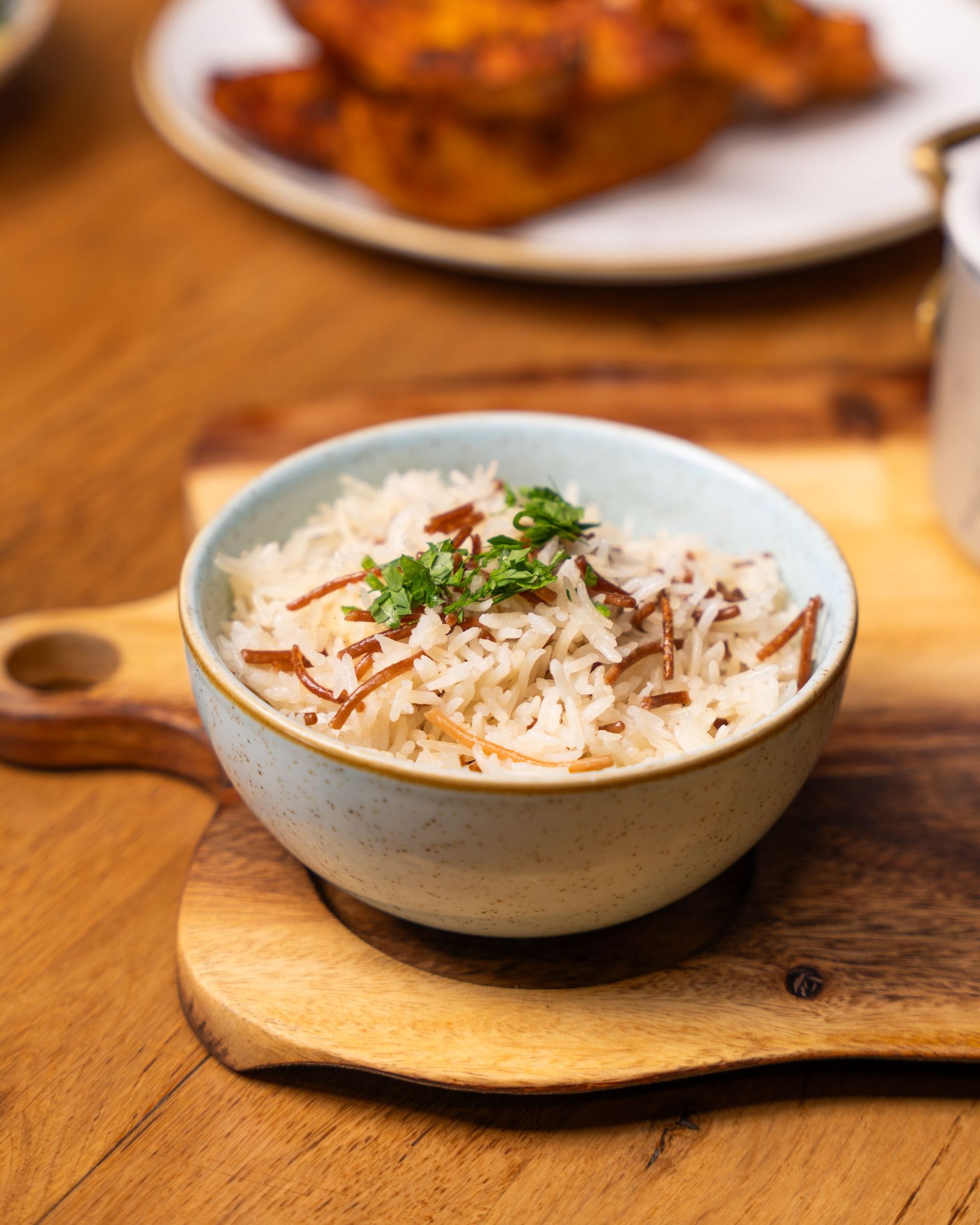 A close-up of aromatic rice garnished with herbs, served in a bowl on a cutting board.