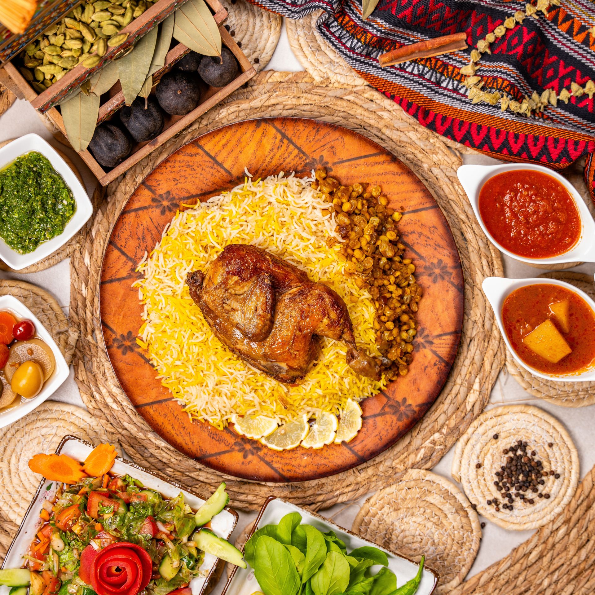 A flavorful Middle Eastern meal featuring roasted chicken on rice with assorted sides and sauces.